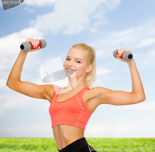 Image of smiling beautiful sporty woman with dumbbells