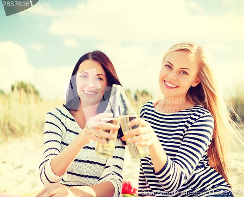 Image of girlfriends with bottles of beer on the beach