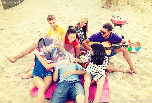 Image of group of friends with guitar having fun on beach
