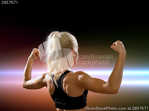 Image of sporty woman from the back flexing her biceps