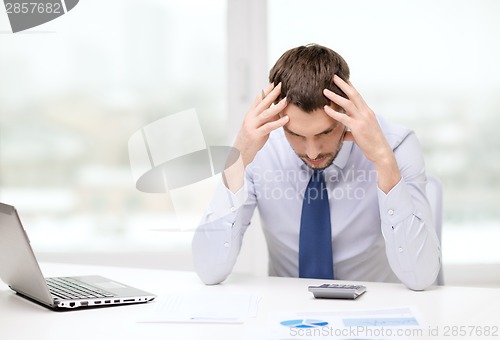 Image of stressed businessman with laptop and documents