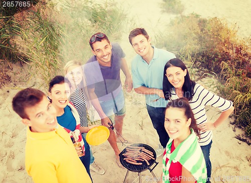 Image of group of friends making barbecue on the beach