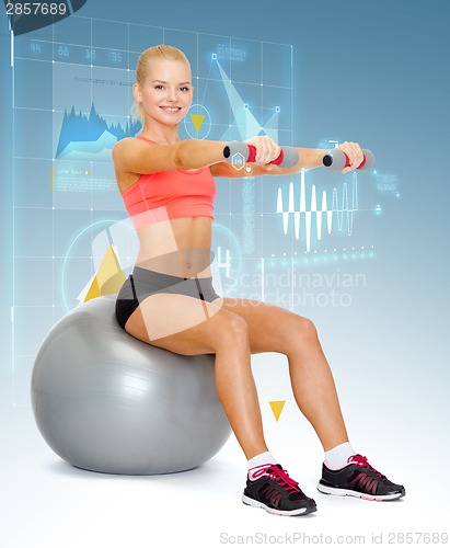 Image of woman with dumbbells sitting on fitness ball