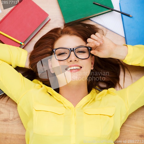 Image of smiling student in eyeglasses lying on floor