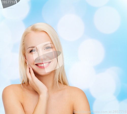 Image of smiling young woman touching her face skin