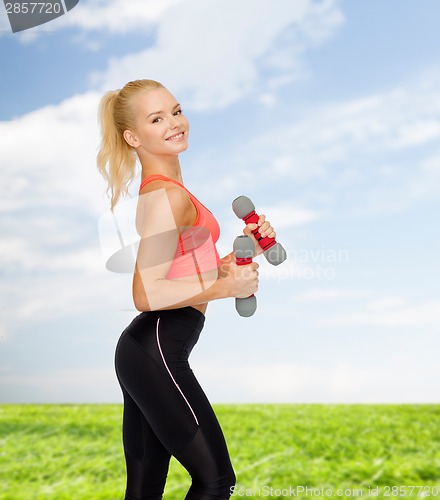 Image of smiling beautiful sporty woman with dumbbells