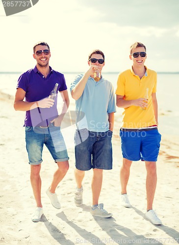 Image of male friends on the beach with bottles of drink