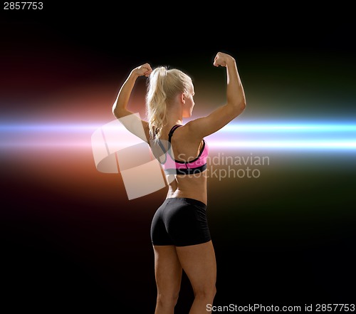 Image of sporty woman from the back flexing her biceps