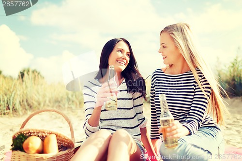 Image of girlfriends with bottles of beer on the beach