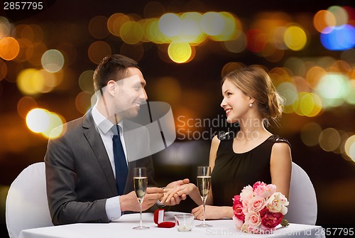 Image of man proposing to his girlfriend at restaurant