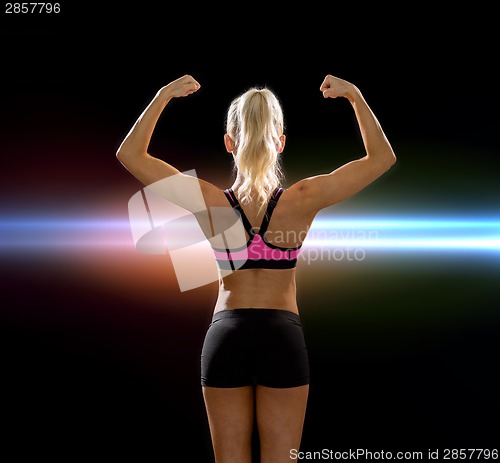 Image of sporty woman from the back flexing her biceps