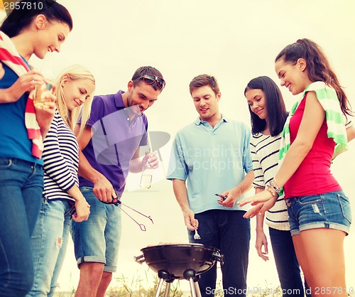 Image of group of friends making barbecue on the beach