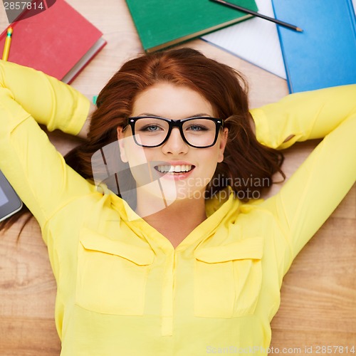 Image of smiling student in eyeglasses lying on floor