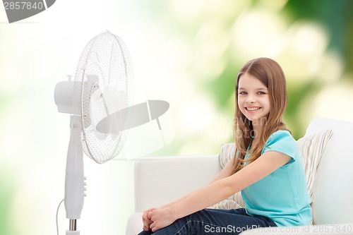 Image of smiling little girl with big fan at home