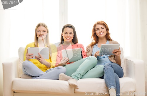 Image of three smiling teenage girls with tablet pc at home