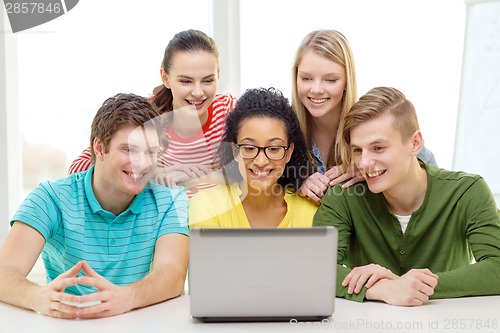 Image of smiling students looking at laptop at school