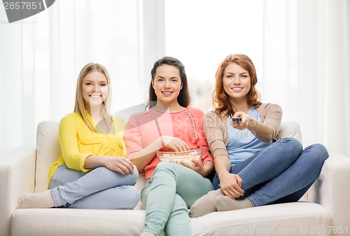 Image of three smiling teenage girl watching tv at home