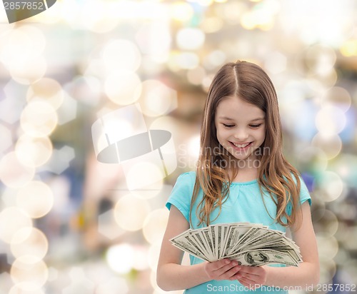 Image of smiling little girl looking at dollar cash money