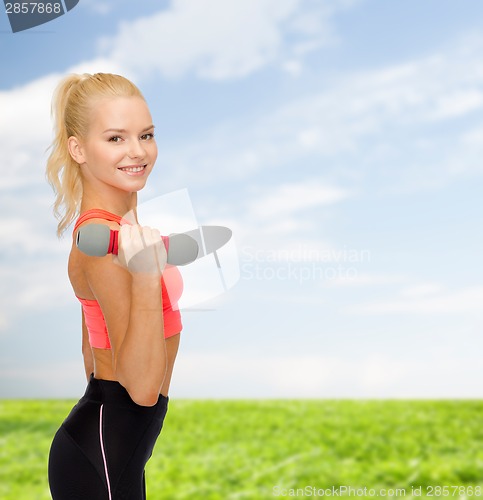 Image of smiling beautiful sporty woman with dumbbell