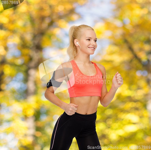 Image of sporty woman running with smartphone and earphones