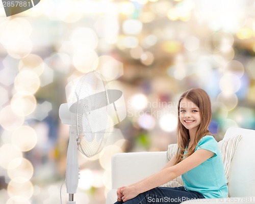 Image of smiling little girl with big fan at home