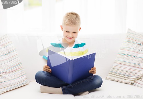 Image of smiling little boy reading book on couch