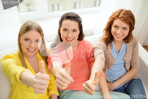 Image of three girlfriends showing thumbs up at home