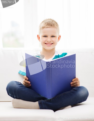 Image of smiling little boy reading book on couch