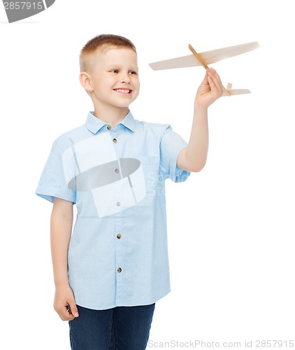 Image of smiling little boy holding a wooden airplane model