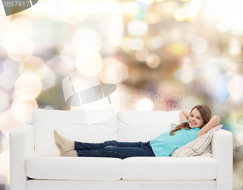 Image of smiling little girl lying on sofa
