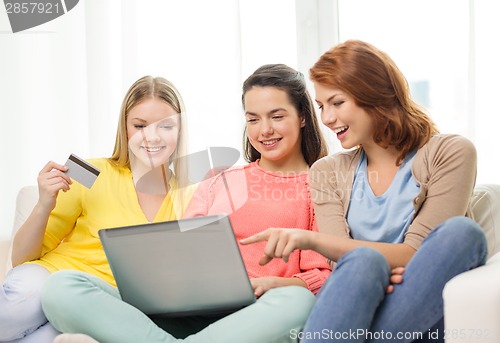 Image of smiling teenage girls with laptop and credit card