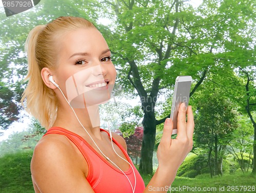 Image of smiling sporty woman with smartphone and earphones