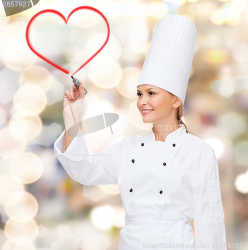 Image of smiling female chef drawing red heart on air