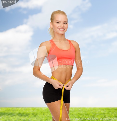 Image of smiling sporty woman with measuring tape