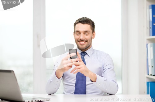 Image of businessman with laptop and smartphone at office