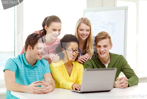 Image of smiling students looking at laptop at school