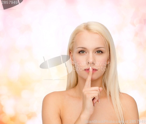 Image of calm young woman with finger on lips