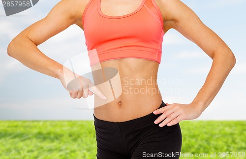 Image of close up of woman pointing finger at her six pack