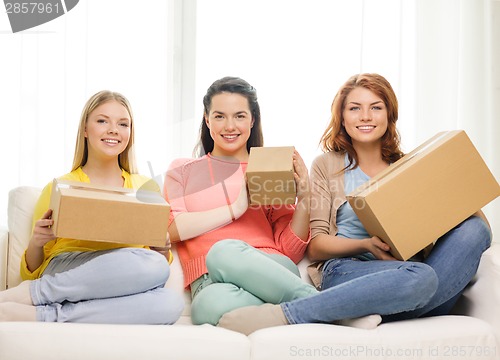 Image of smiling teenage girls with cardboard boxes at home