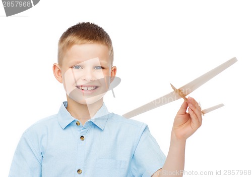 Image of smiling little boy holding a wooden airplane model