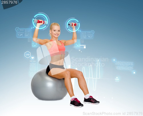 Image of woman with dumbbells sitting on fitness ball