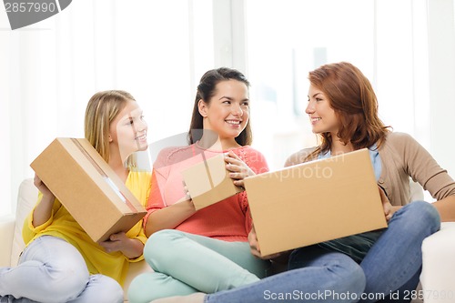 Image of smiling teenage girls with cardboard boxes at home