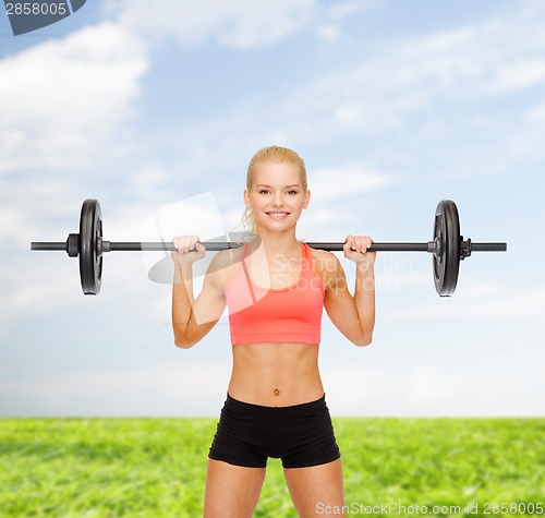 Image of smiling sporty woman exercising with barbell