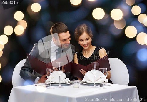 Image of smiling couple with menus at restaurant