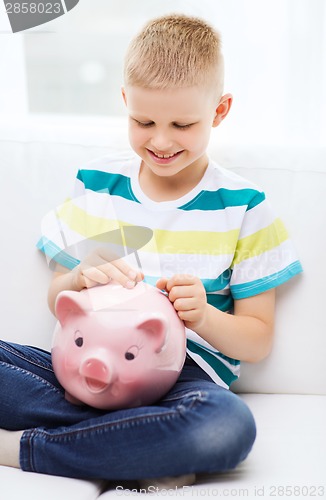 Image of smiling little boy with piggy bank and money