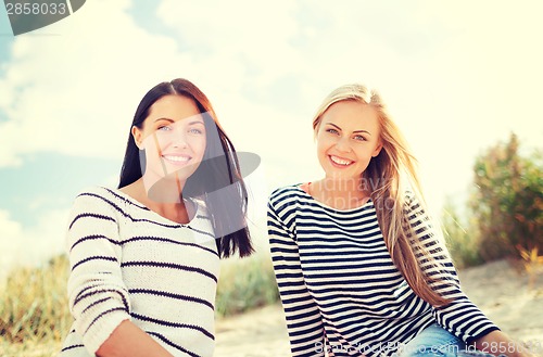 Image of smiling girlfriends having fun on the beach