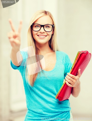 Image of smiling student with folders showing victory sign