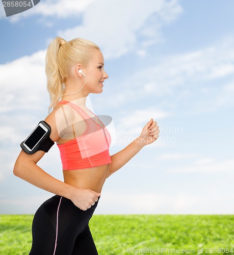 Image of sporty woman running with smartphone and earphones