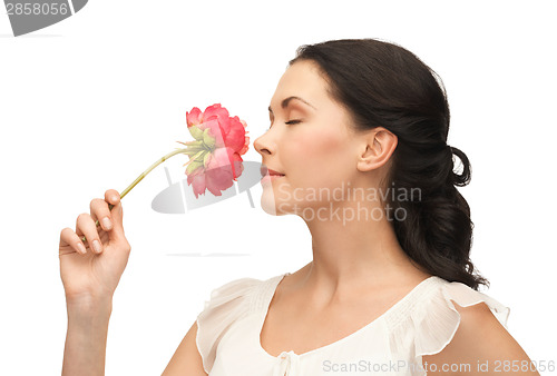 Image of young and beautiful woman smelling flower