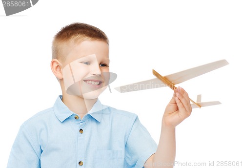 Image of smiling little boy holding a wooden airplane model